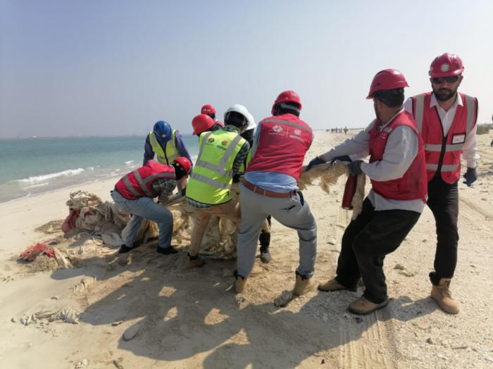 中國(guó)電建員工在撿拾海灘垃圾。中國(guó)電建供圖